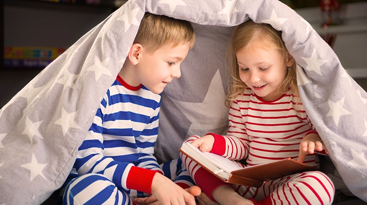 bambini che leggono sotto il piumone - AL1331344